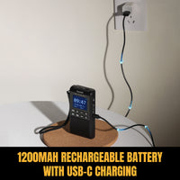 Black portable device with Raddy RD939 digital display on a cork coaster, plugged into a wall socket with text '1200mAh rechargeable battery with USB-C charging'.